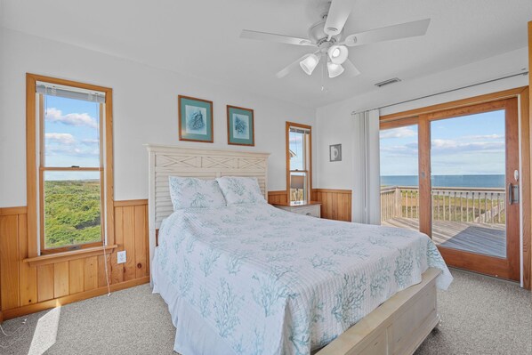A bedroom with a bed, a ceiling fan, and a view of the ocean through a sliding glass door. - Soundfront Home w/ Hot Tub, Easy Windsports Access, Sound Boardwalk, and More! (Frisco)