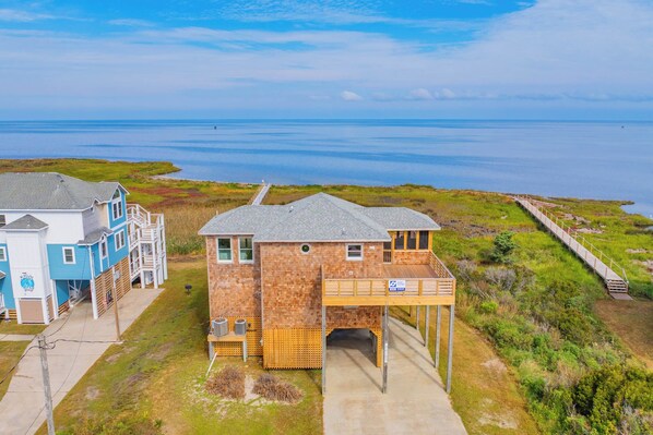 A coastal property with a main house, a secondary building, and a wooden deck leading to a dock.