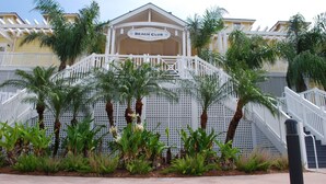 A building with a sign reading "Beach Club" and a staircase leading to a covered area. - Beachfront and steps away from the Beach Club at Pointe West, get Serenity Now (Galveston)
