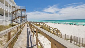 A wooden boardwalk leading to a beach with a white building on the left. - Right on the Beach! Sleeps 10
7 day rentals incl. setup of 4 chairs/2 umbrellas (Seagrove Beach)