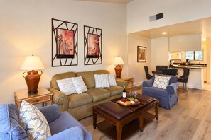 Uma sala de estar com sofá, mesa de centro e um espaço de jantar com cadeira e mesa.