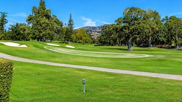 A well-maintained golf course with a clear path, sand bunkers, and a variety of trees.