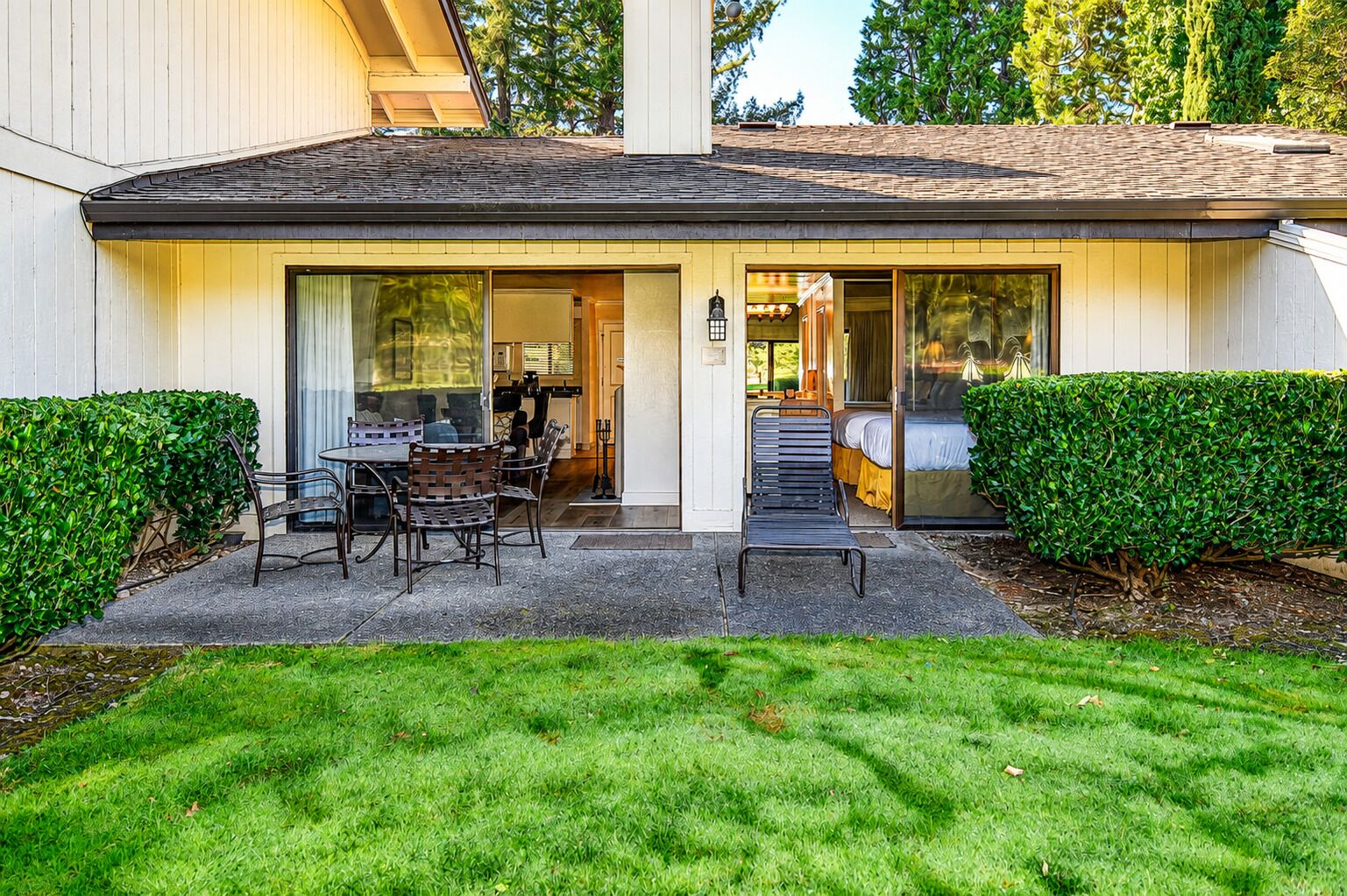 A modern house with a patio, a dining area, and a bedroom with a sliding glass door.