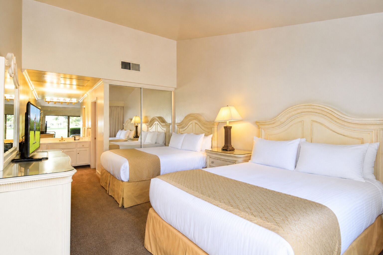Habitación de hotel con dos camas, un televisor, un espejo y una lámpara.