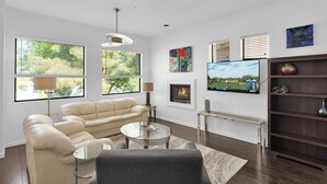 Ein modernes Wohnzimmer mit einer Couch, einem Couchtisch, einem Kamin und einem an der Wand befestigten Fernseher.
