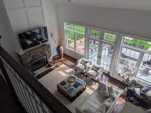 A spacious living room with a fireplace, comfortable seating, and large windows offering a view of the outdoors. - Hampton Private Retreat - last minute offer June 23- (Southampton)