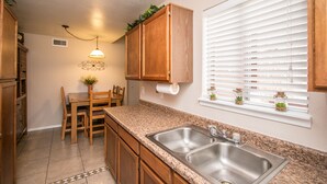 A kitchen with granite countertops, wooden cabinets, a double sink, and a window with blinds. - GREAT condo rental conveniently located in Mesa/Phoenix   (Mesa)