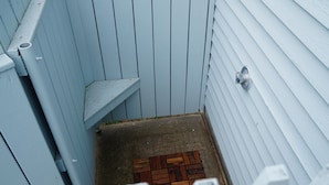 Een smal, afgesloten buitenruimte met een houten vloer en een metalen deur.
