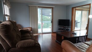 Een woonkamer met een bruine leren bank, een houten salontafel en een flatscreen televisie.
