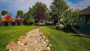 A well-maintained backyard with a gravel path, a gazebo, and a lawn. - Claim Jumpers Cottage (Baker City)