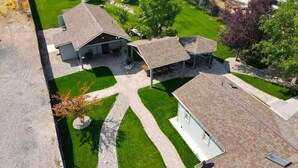 A residential property with a large house, a covered patio, and a well-maintained lawn. - Claim Jumpers Cottage (Baker City)