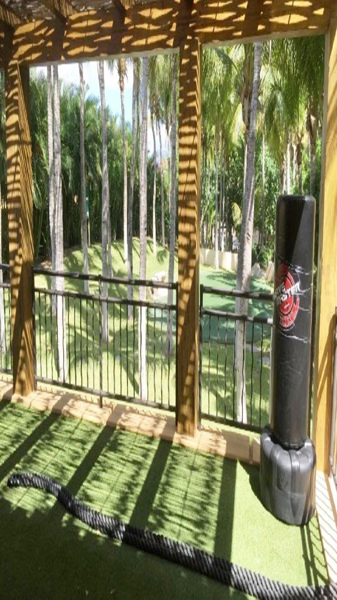 Un espace abrité, délimité par une barrière faite de cordes, avec un sac de frappe et une vue sur un terrain de golf.