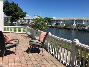 Relax on the waterfront patio with two comfortable chairs and a serene view of the water and surrounding buildings.