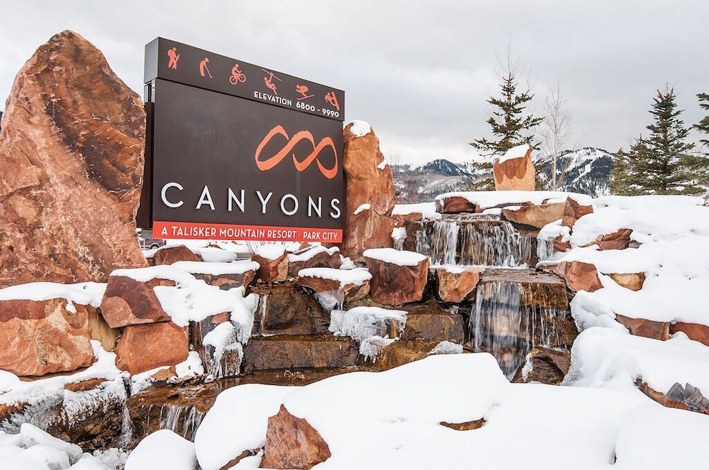 A sign for Canyon's Talisker Mountain Resort with a waterfall and snow-covered rocks.