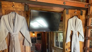 A rustic cabin interior with wooden walls, a fireplace, and two robes hanging on a wooden door. - TREE CABIN FOR 2🌲Unique cabin close to San Luis Obispo, Morro Bay & Paso Robles (Templeton)