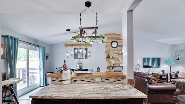 Een moderne keuken met een marmeren aanrechtblad, een hanglamp en een houten accentmuur.
