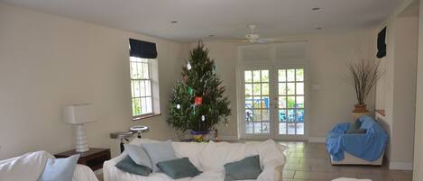 A living room with a white couch, a coffee table, and a Christmas tree.