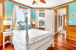Classic four-poster bed and a cozy nightstand with a lamp, set against a window with curtains.