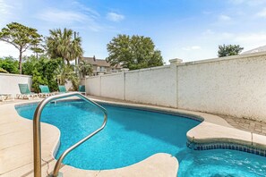 Relax by the pool surrounded by lush greenery and a palm tree.