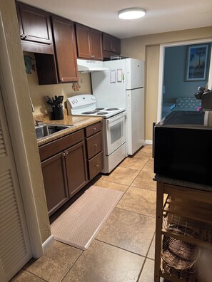 A kitchen with brown cabinets, a white stove, and a refrigerator.