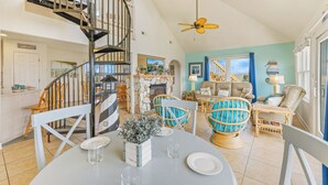 A spacious living area with a dining table, chairs, a spiral staircase, and a cozy seating area with a sofa and armchairs.