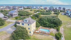 A coastal residential area with houses, a swimming pool, and a view of the sea.