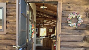 Interior de una cabaña de madera con cocina, un tapete rojo y una guirnalda en la pared.