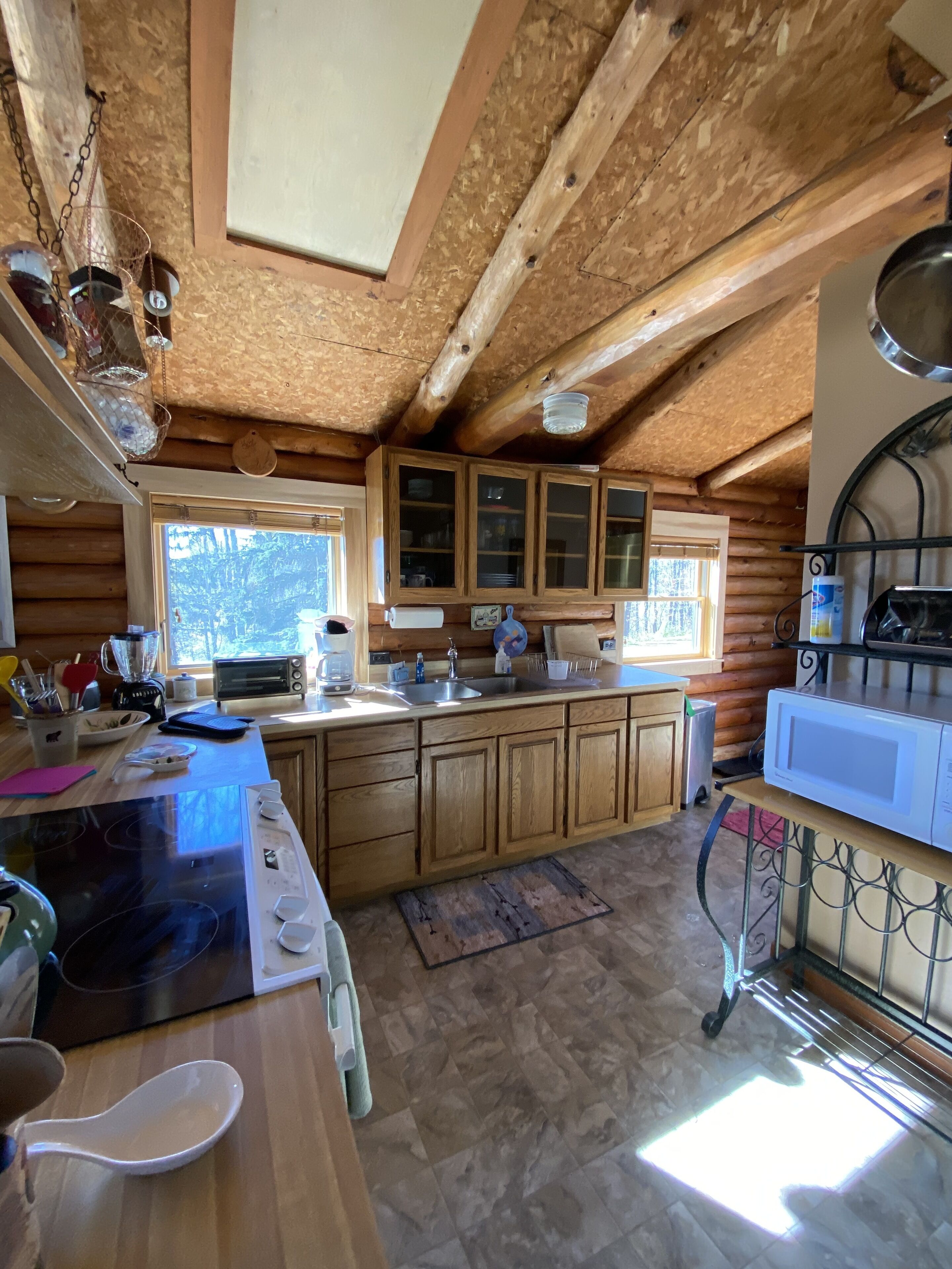 A rustic kitchen with wooden cabinets, a stove, and a sink.