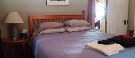 A bedroom with a bed, a nightstand, a lamp, and a framed picture on the wall.
