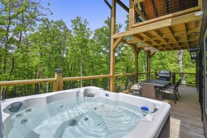 Un bain à remous sur une terrasse en bois, avec vue sur une forêt.