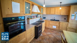 A kitchen with wooden cabinets, a stove, oven, and a microwave. - Villa Gentilini, nature & comfort (Serrada)