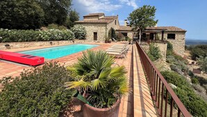 Una villa de piedra con piscina, zona de estar al aire libre y vistas al paisaje.