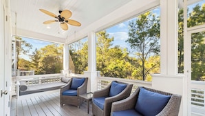 A covered porch with wicker furniture and a ceiling fan. - Luxury Coastal Living • Breezy Partially Screened Porch & Lagoon Pool Access (Seacrest Beach)