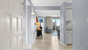 A hallway with a dining area, kitchen, and a view of the outside. - Destin West Heron 607 ~ Beach Paradise ~ All the Upgrades ~ Overlooking the Lazy River (Fort Walton Beach)