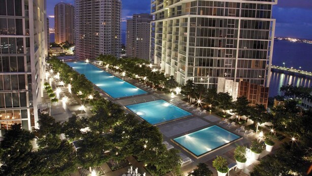 A high-rise building with a rooftop pool area surrounded by trees and lounge chairs. - Prime Brickell Suite | Walk to City Center (Miami)