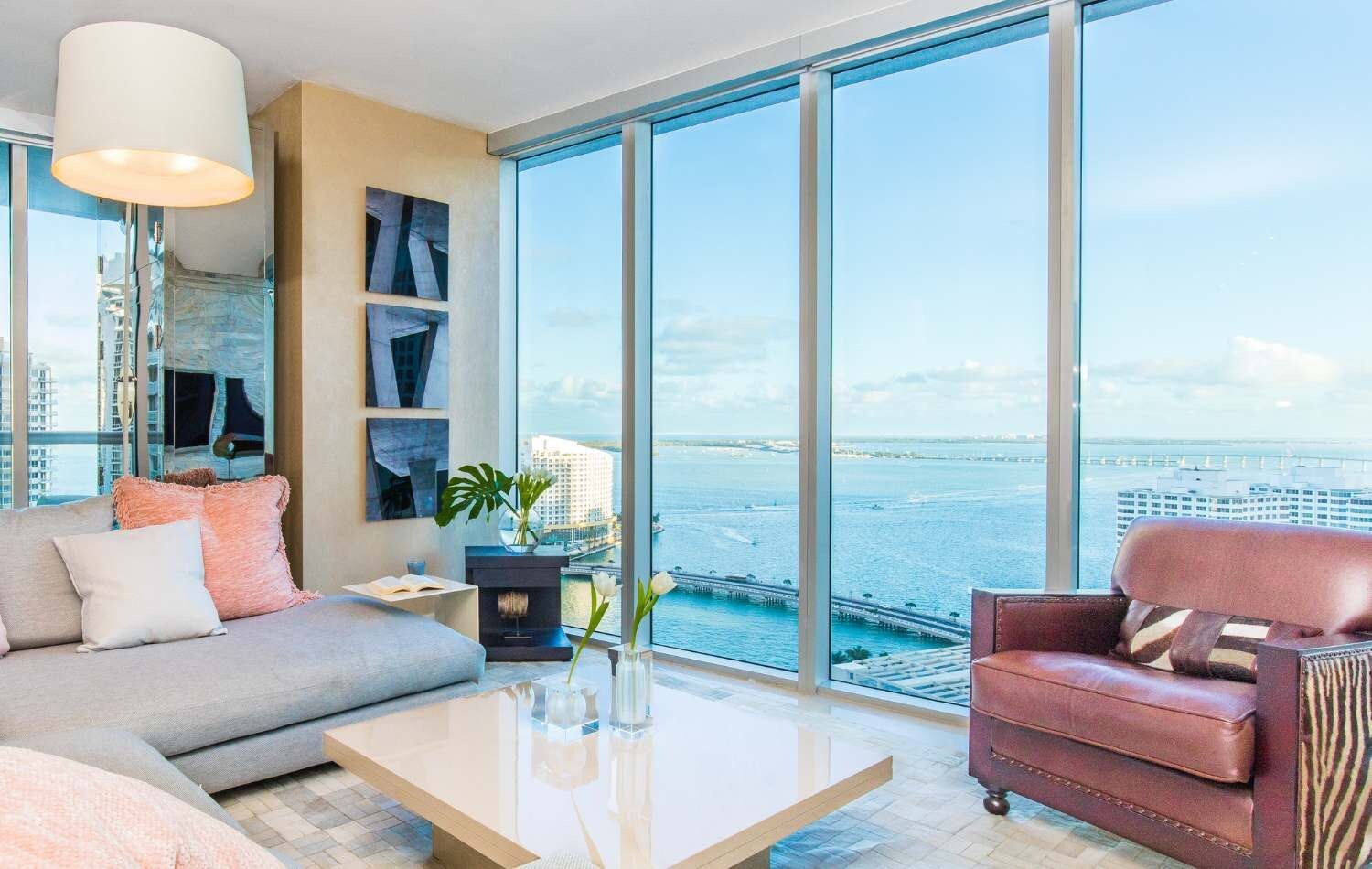 Ein modernes Wohnzimmer mit Sofa, Sessel, Couchtisch und Blick auf das Wasser.