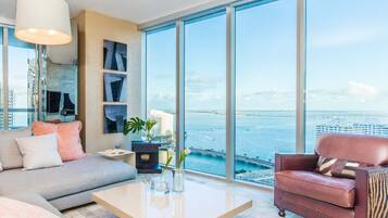 Un salon moderne avec un canapé, un fauteuil, une table basse et une vue sur l’eau.