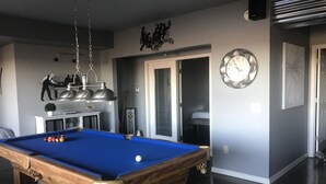A pool table with balls, a clock, and a door leading to another room. - Beaver Lake Get-a-Way          Great Location--Beautiful View (Rogers)