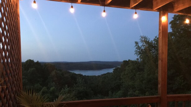 A wooden deck with a railing overlooking a lake surrounded by trees. - Beaver Lake Get-a-Way          Great Location--Beautiful View (Rogers)