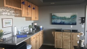 A kitchen with wooden cabinets, a coffee maker, and a painting on the wall. - Beaver Lake Get-a-Way          Great Location--Beautiful View (Rogers)