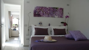 Un dormitorio con una cama, un edredón morado, un sombrero de paja y una almohada morada.