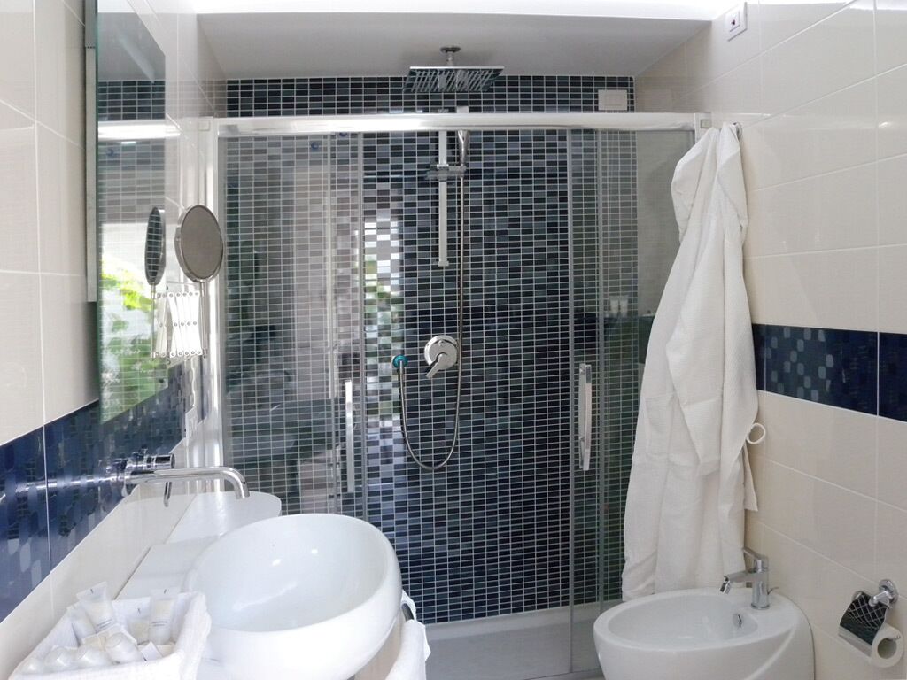 Un bagno moderno con doccia vetrata, lavandino bianco e water.