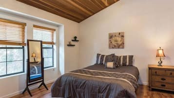 A bedroom with a large bed, wooden ceiling, and a nightstand with a lamp.