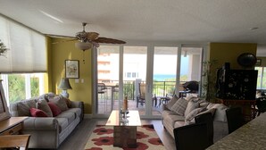 A spacious living room with a large sliding glass door leading to a balcony with a view of the ocean. - Luxurious, Newer Oceanfront, Professionally Decorated, Beautiful Condo (Cocoa Beach)