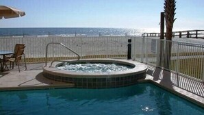 Una piscina con hidromasaje, una silla y una mesa en un patio con vista al océano.