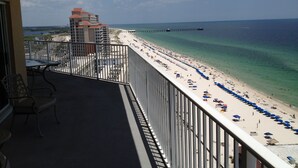 Un balcón con vista a una playa, un muelle y un edificio de hotel.