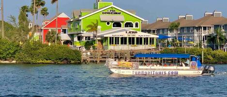 Un restaurant situé au bord de l’eau, avec une façade verdoyante et un bateau amarré à proximité.