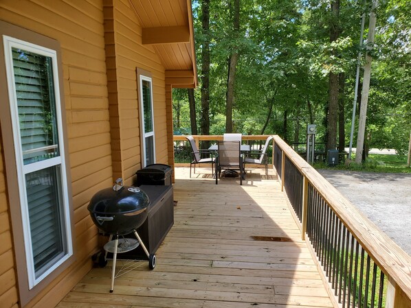 A wooden deck with a barbecue grill and outdoor furniture.