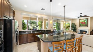 Una cocina moderna con una isla grande, sillas de madera y una mesa de comedor.