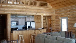 A log cabin interior with a kitchen, dining area, and living room. - Special Labor Day Weekend! The cabin is available for 6-8 guests in 3 bedrooms. (Longville)